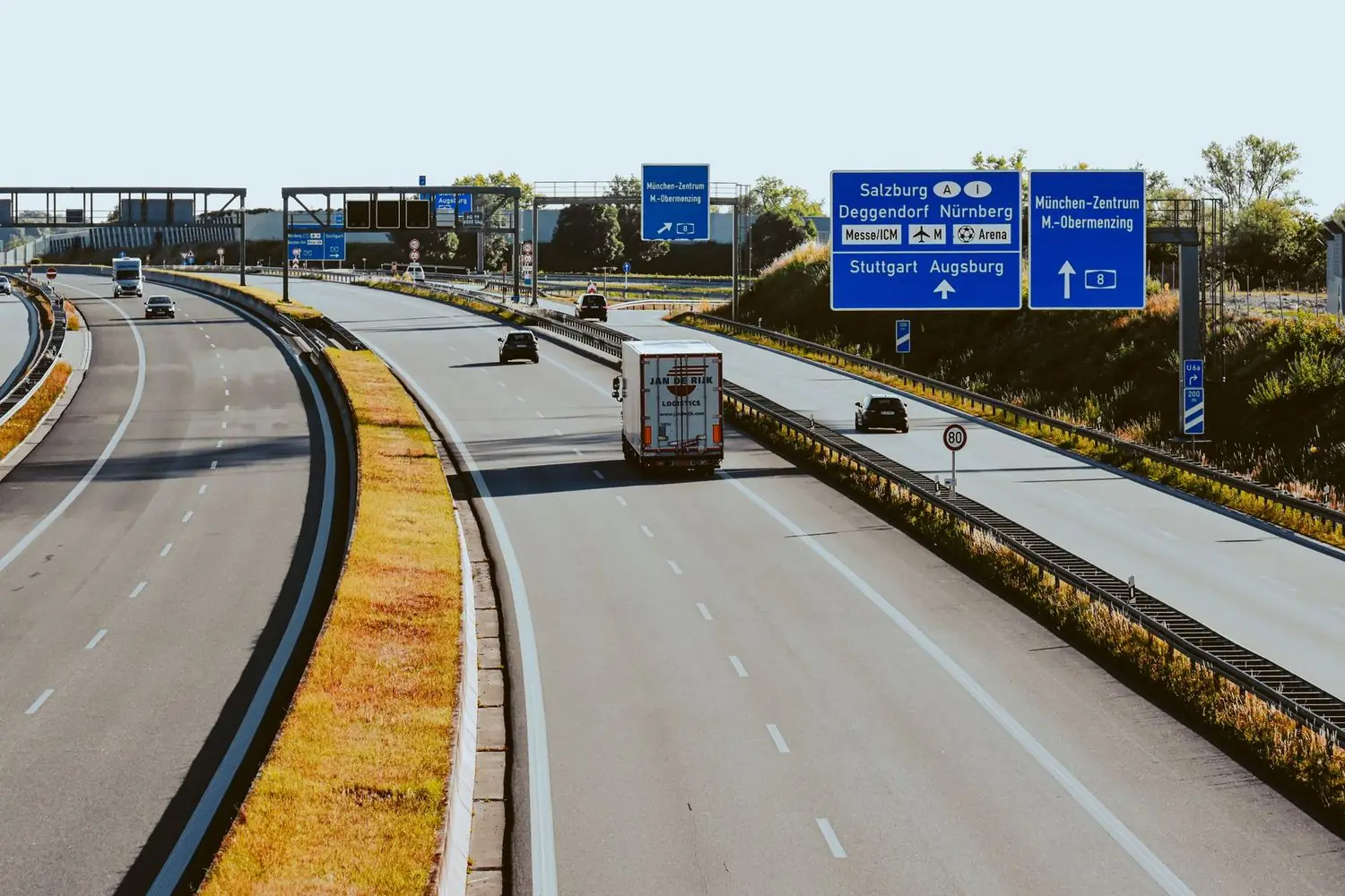 Panouri albastre de direcție pe o autostradă, cu o limită de 80 afișată pe sector