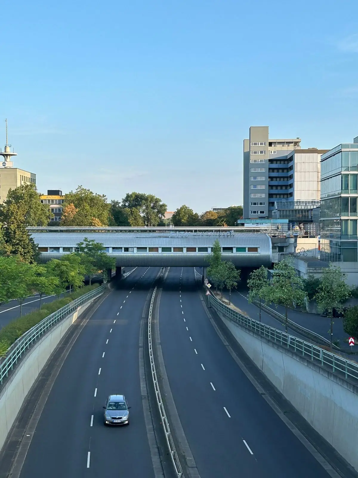 Autostradă care trece pe sub un pod, într-un peisaj de oraș